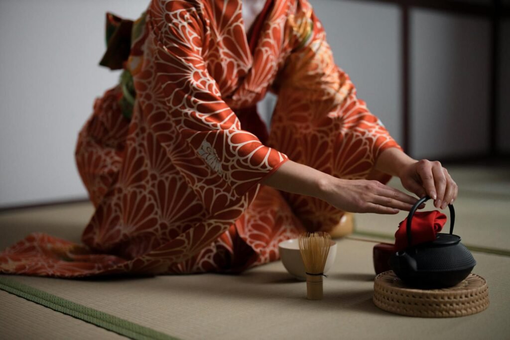 Close-up of a woman in kimono preparing for a Japanese tea ceremony indoors.