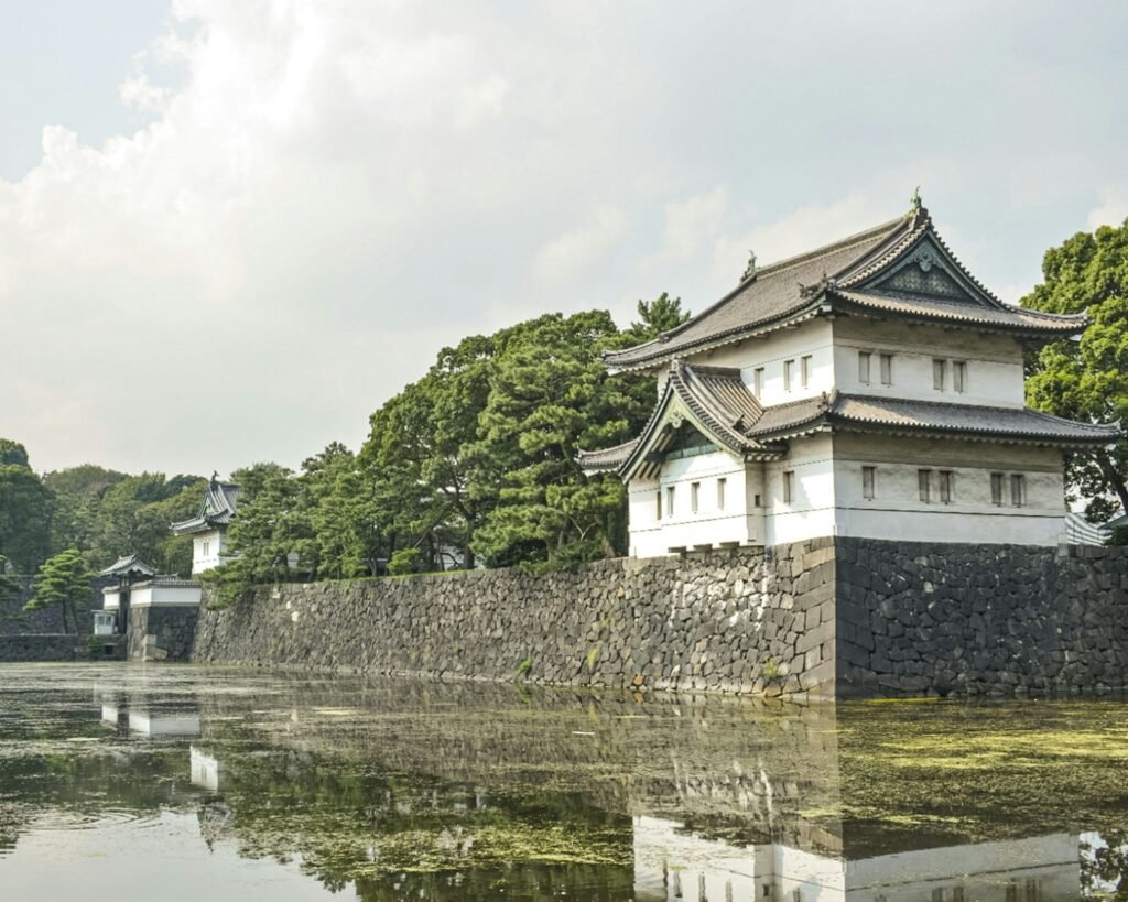 a building with a stone wall and trees in the background