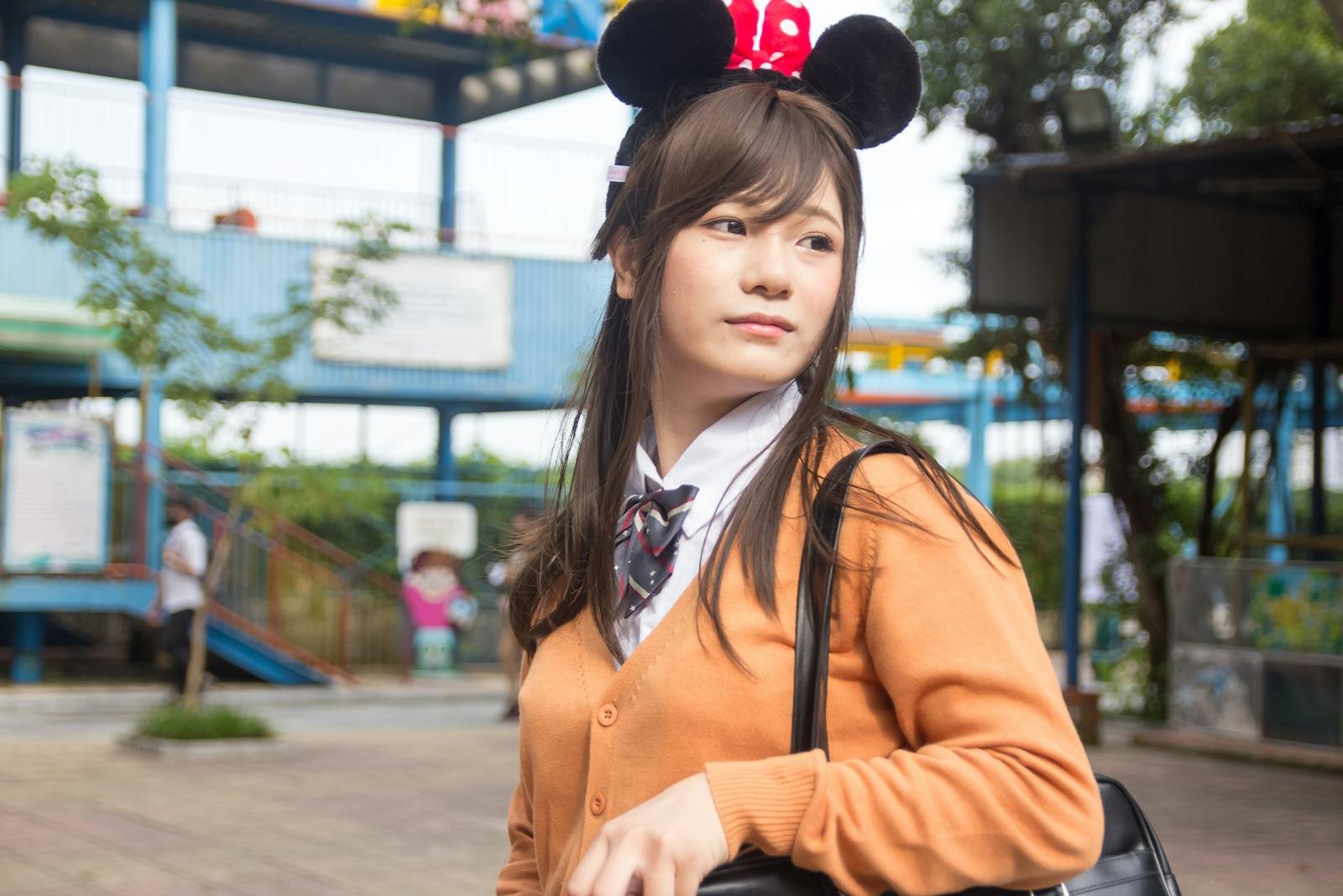 Portrait of a young woman with a playful headband, outdoors at an amusement park.