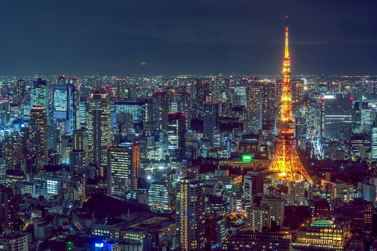 Stunning aerial view of Tokyo's vibrant cityscape with the illuminated Tokyo Tower at night.