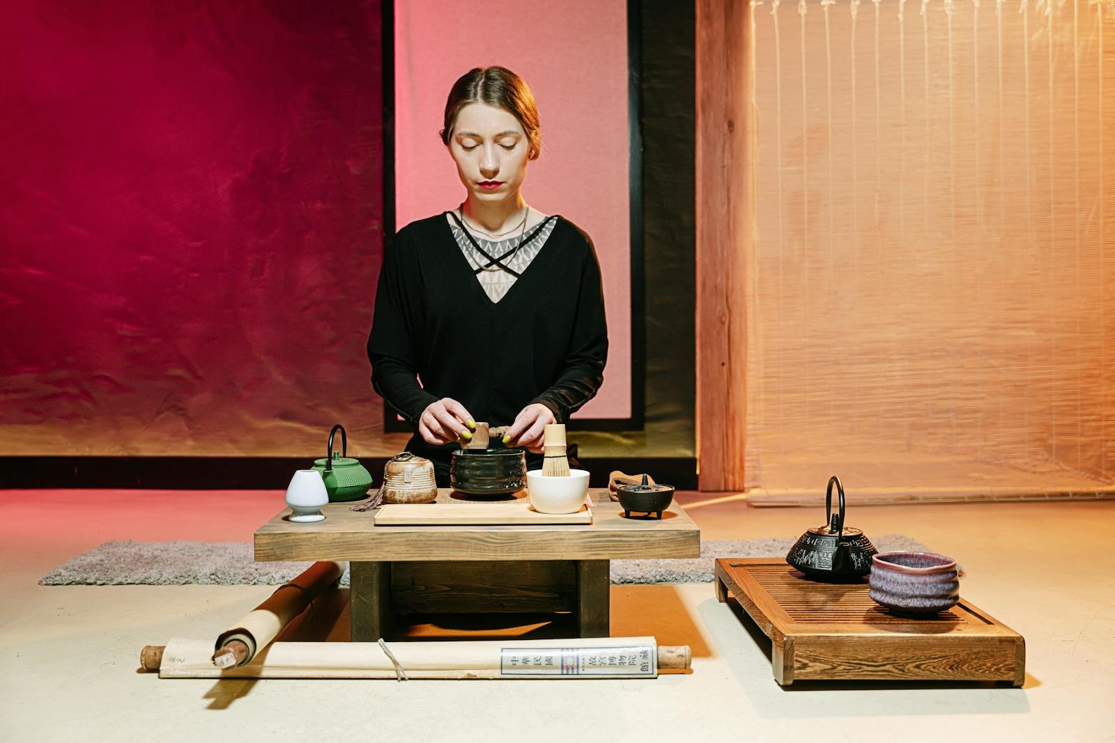 A serene Japanese tea ceremony featuring a woman preparing tea with traditional utensils indoors.