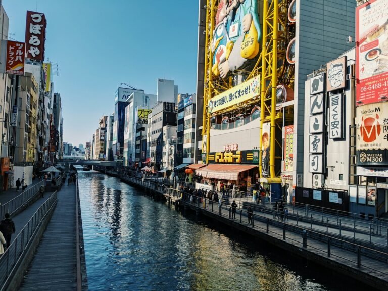 people walking on sidewalk beside river during daytime Osaka